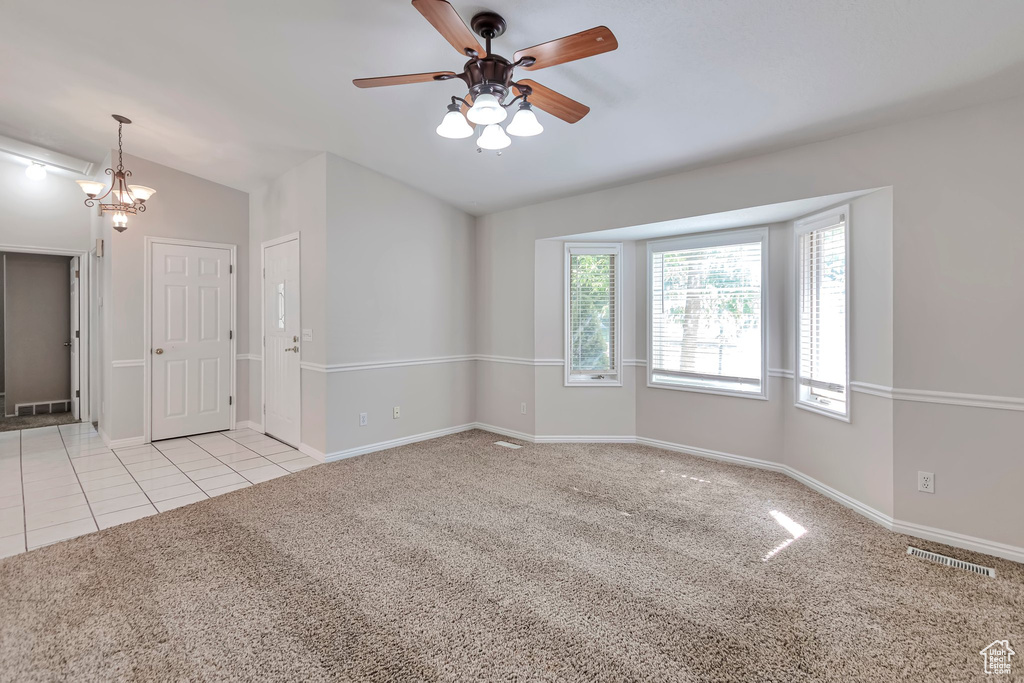 Carpeted spare room with ceiling fan, lofted ceiling, and tile patterned flooring