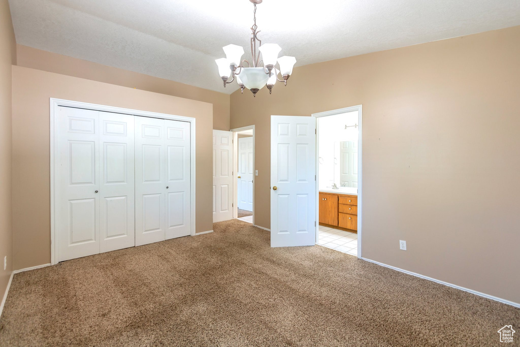 Unfurnished bedroom with a chandelier, light carpet, a closet, and connected bathroom