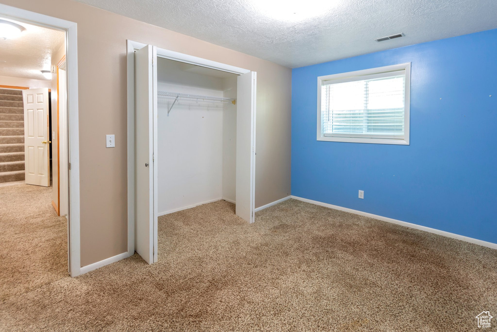 Unfurnished bedroom with carpet flooring, a closet, and a textured ceiling