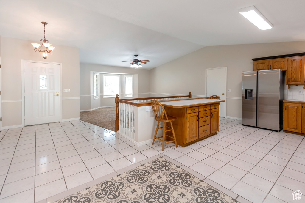 Kitchen with stainless steel refrigerator with ice dispenser, light countertops, lofted ceiling, ceiling fan, and light tile patterned floors