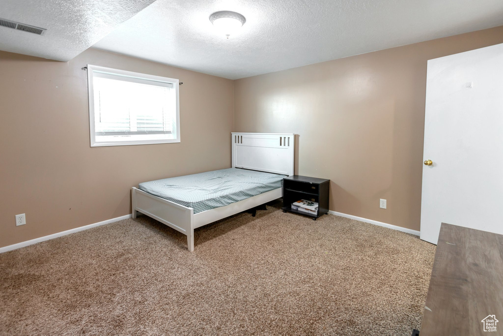 Bedroom with a textured ceiling and carpet