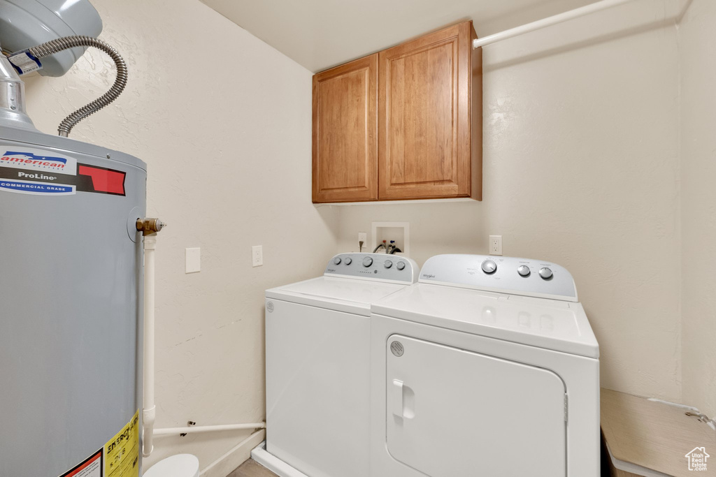 Laundry room featuring gas water heater, washing machine and dryer, and cabinet space