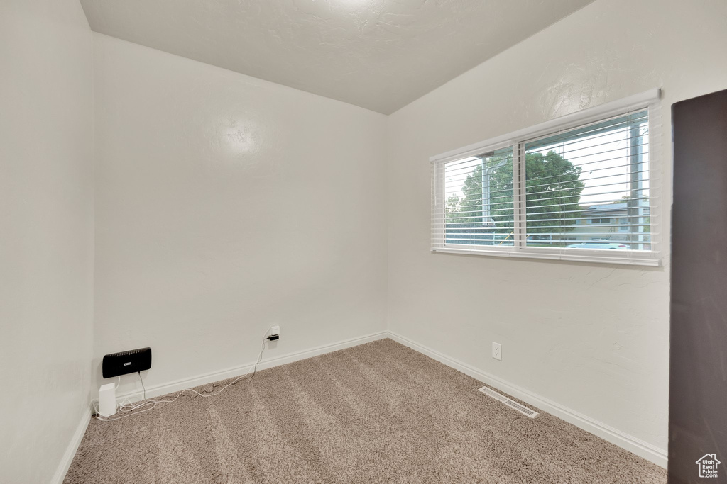 Carpeted spare room featuring baseboards