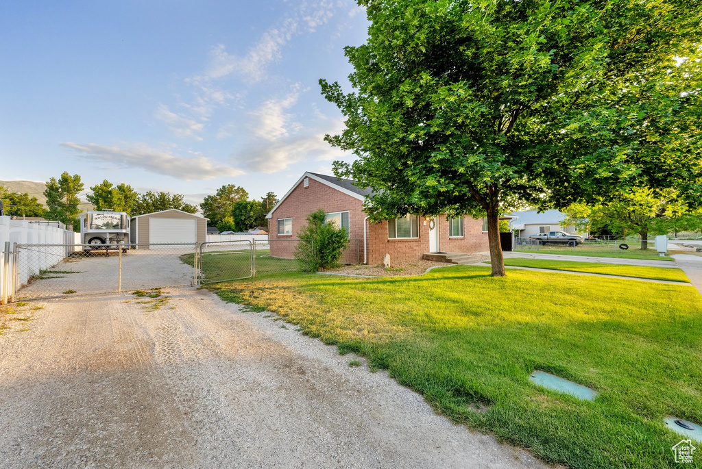 View of front of home with driveway, a garage, brick siding, and an outdoor structure