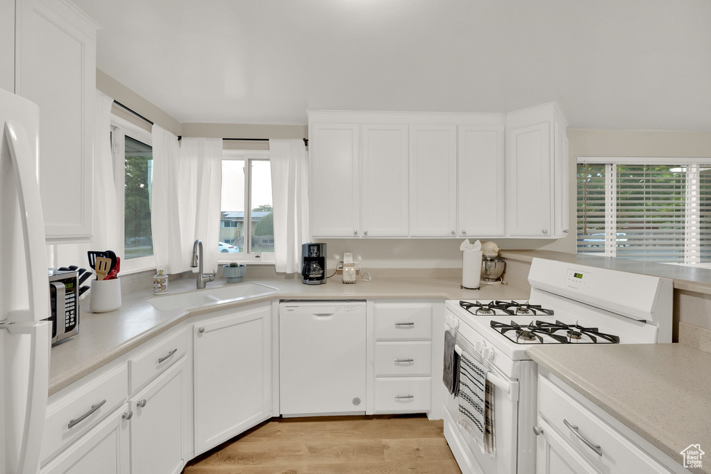 Kitchen with white appliances, a sink, white cabinetry, and light countertops