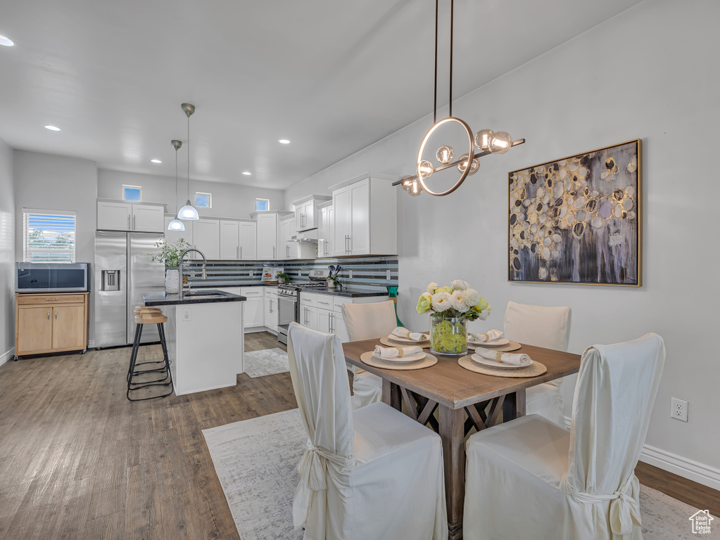 Dining space featuring wood finished floors, a chandelier, recessed lighting, and baseboards