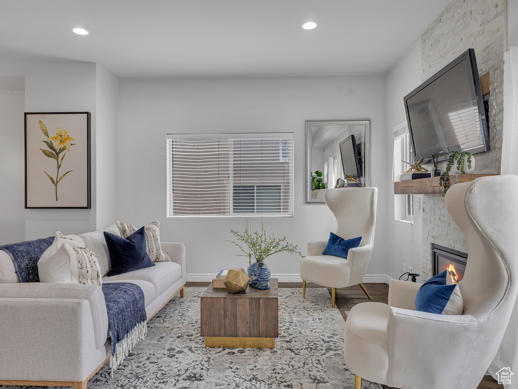 Living area featuring a stone fireplace, wood finished floors, baseboards, and recessed lighting