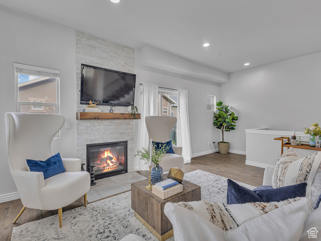Living room with a fireplace, wood finished floors, baseboards, and recessed lighting