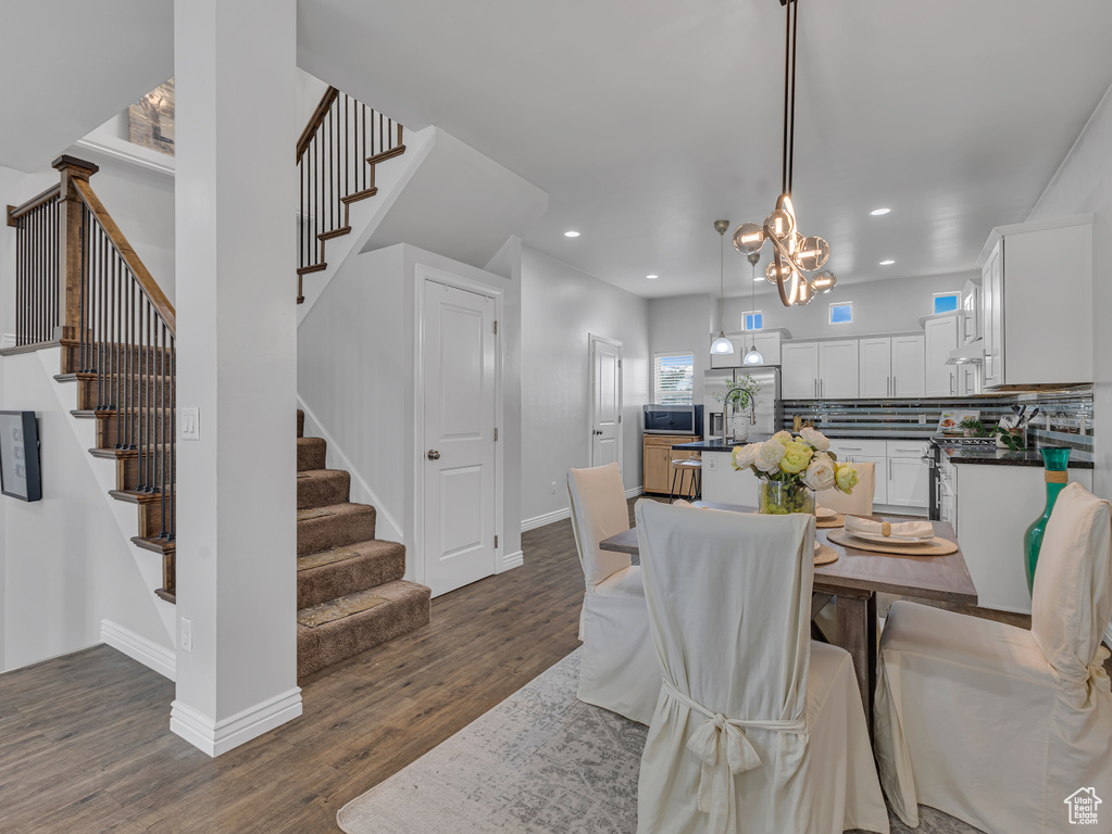 Dining space with dark wood finished floors, stairs, recessed lighting, a chandelier, and baseboards