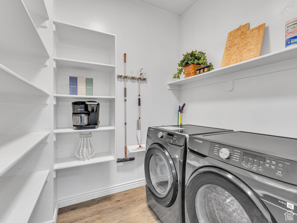 Laundry room featuring washer and dryer, wood finished floors, and baseboards