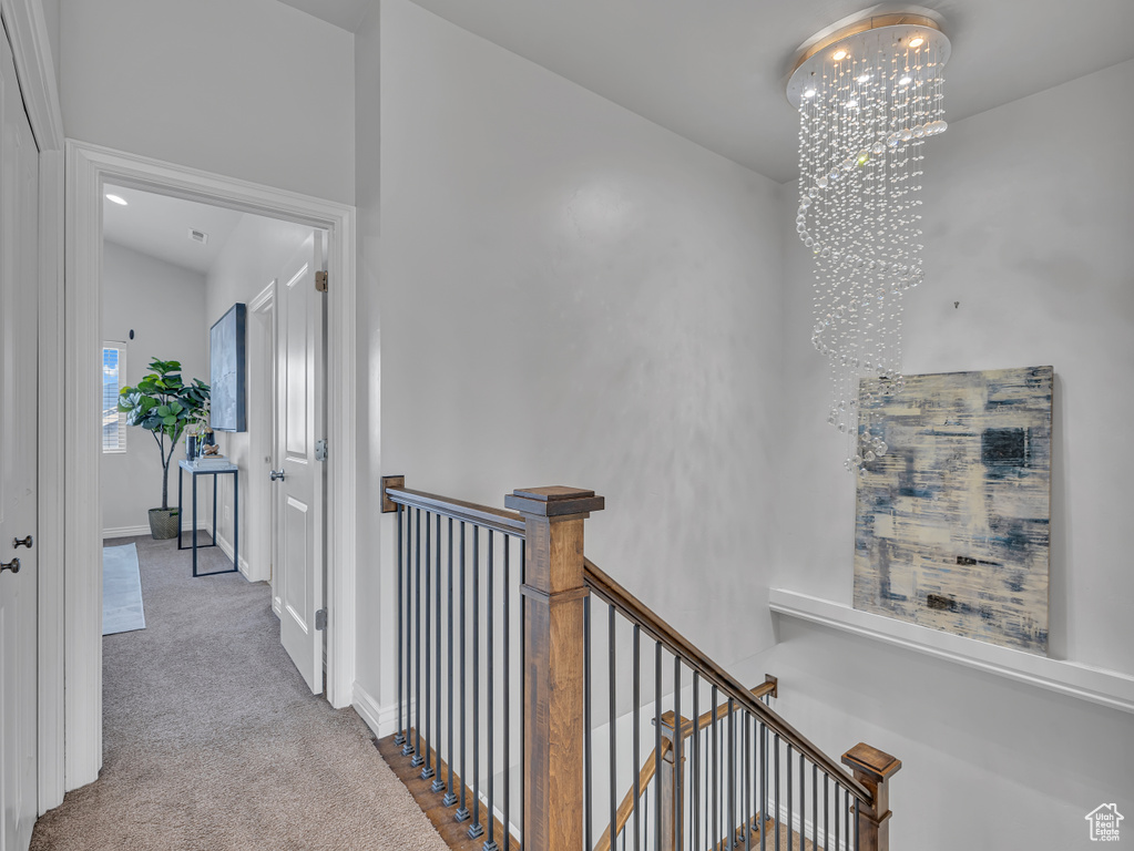 Corridor featuring an upstairs landing, a chandelier, carpet flooring, and baseboards