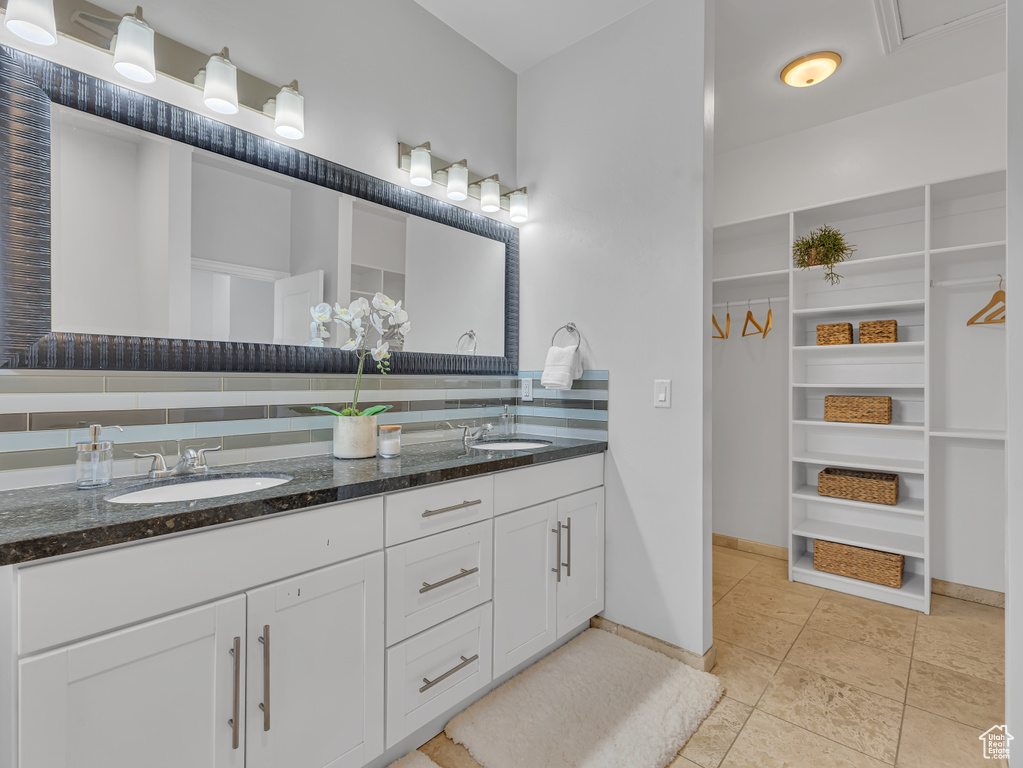 Bathroom featuring double vanity, a walk in closet, baseboards, and tile patterned floors