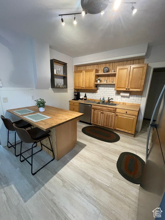 Kitchen with dishwasher, open shelves, track lighting, a wainscoted wall, and backsplash