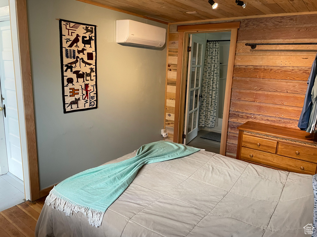 Bedroom with a wall unit AC, wooden ceiling, and wood-type flooring