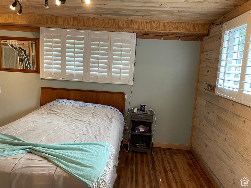 Bedroom with rail lighting, wood walls, hardwood / wood-style flooring, and wood ceiling