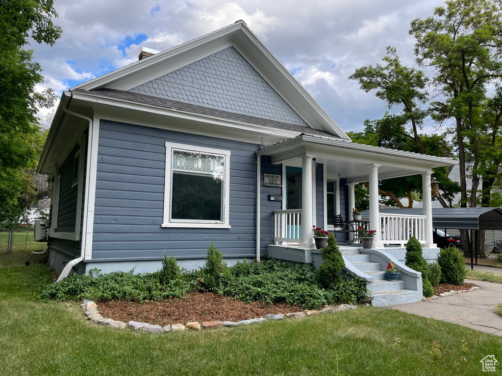 View of front of home featuring a porch, a front yard, and a carport