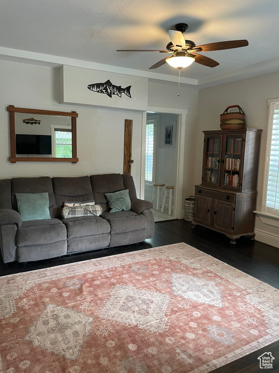 Living area with ceiling fan and dark wood-type flooring