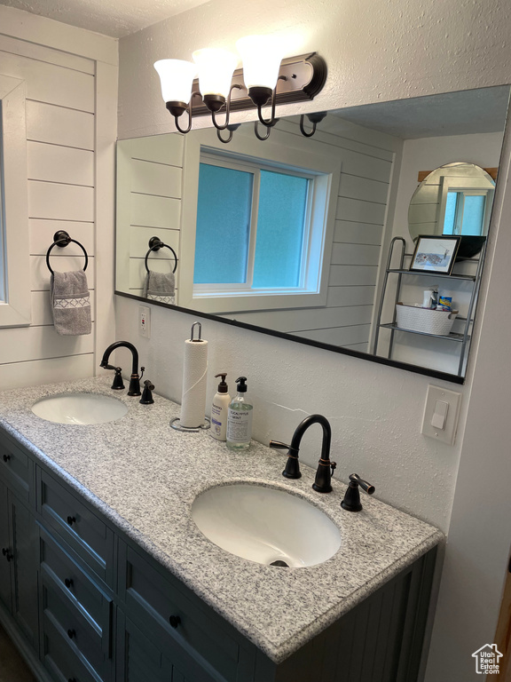 Bathroom with double vanity, a textured ceiling, and a chandelier