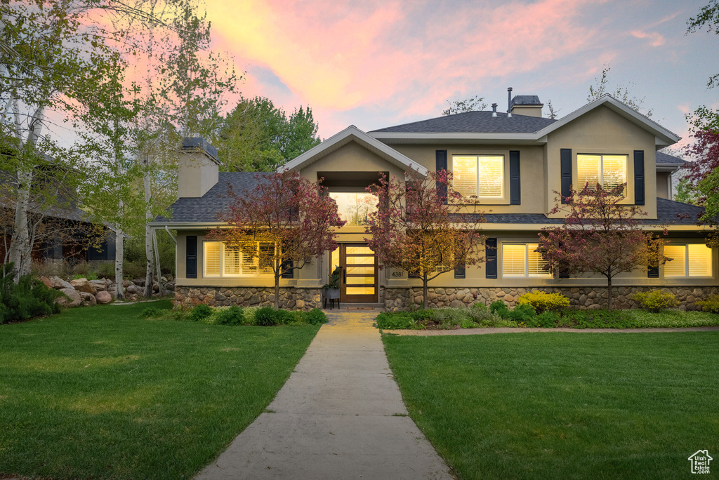 View of front of property with a chimney, stone siding, and a front lawn