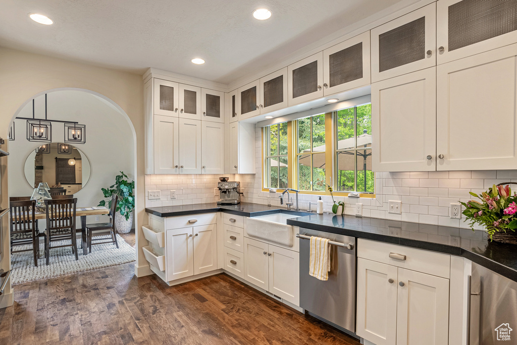 Kitchen featuring dishwasher, a sink, dark wood-style flooring, recessed lighting, and dark countertops