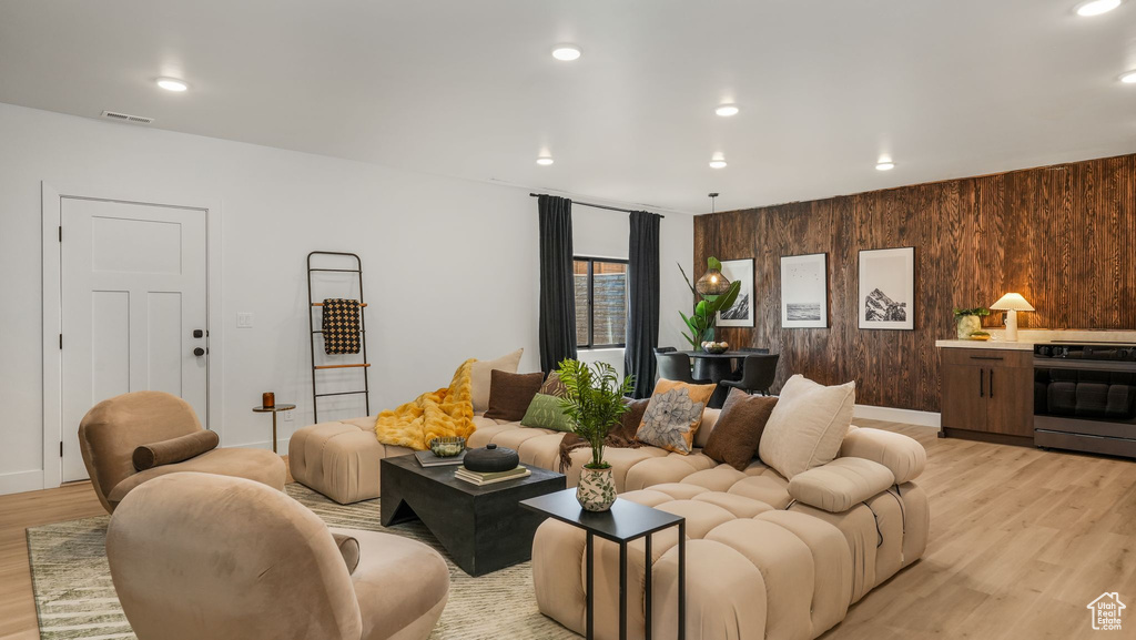 Living area featuring light wood-type flooring, wood walls, and recessed lighting