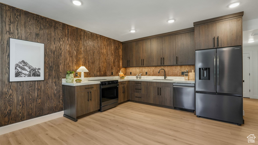 Kitchen featuring appliances with stainless steel finishes, light countertops, light wood-style floors, a sink, and dark brown cabinetry