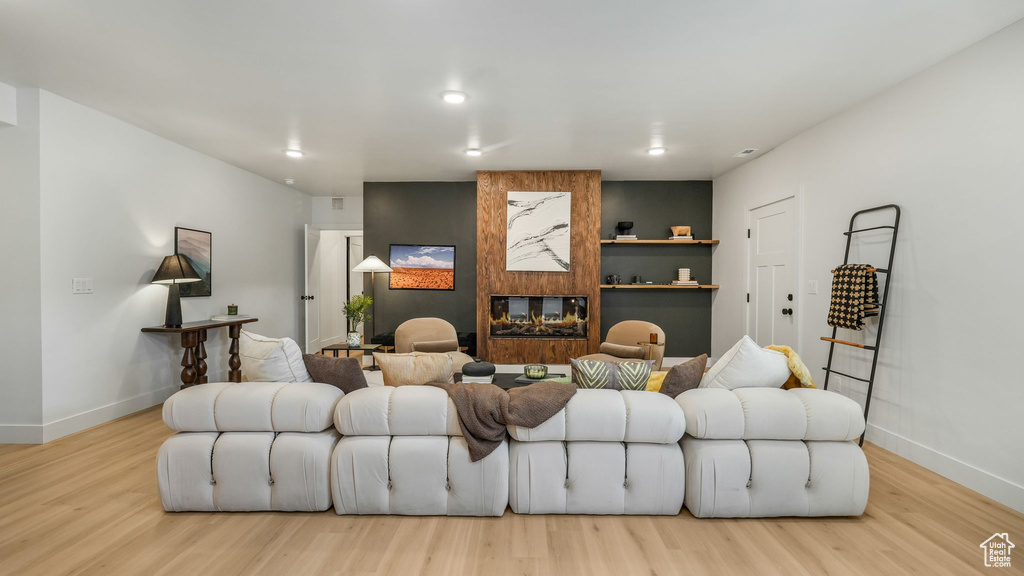 Living area with baseboards, wood finished floors, a large fireplace, and recessed lighting