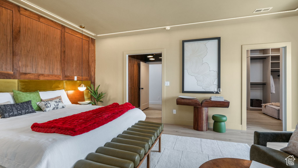 Bedroom featuring a walk in closet, light wood-style floors, and baseboards