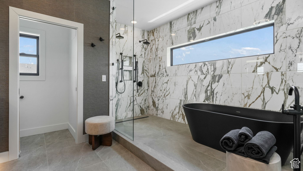 Full bath featuring a marble finish shower, a freestanding tub, tile patterned flooring, and baseboards