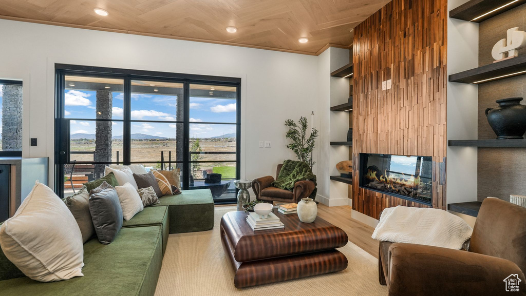 Living room featuring built in features, wood finished floors, a multi sided fireplace, recessed lighting, and baseboards