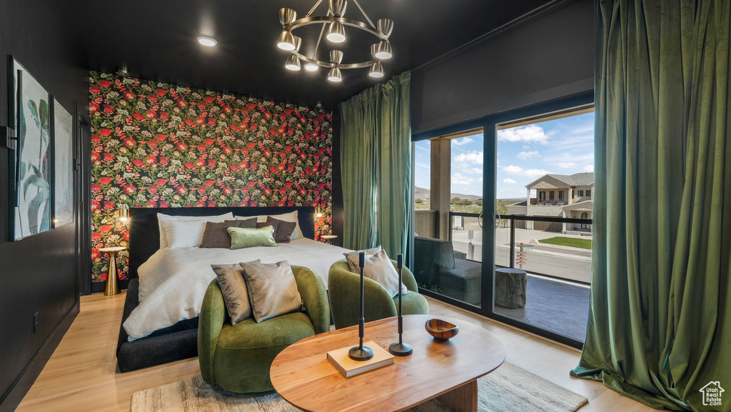 Bedroom with wallpapered walls, access to outside, a chandelier, wood finished floors, and an accent wall