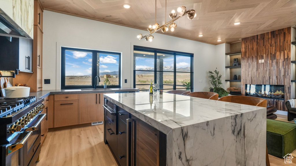 Kitchen with a sink, wine cooler, ventilation hood, high end stove, and a chandelier