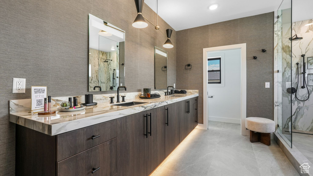 Full bathroom with a marble finish shower, double vanity, and baseboards