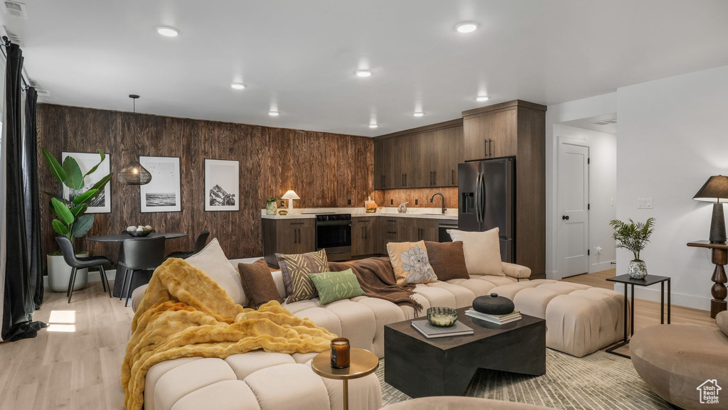 Living room featuring light wood-style floors, baseboards, wooden walls, and recessed lighting