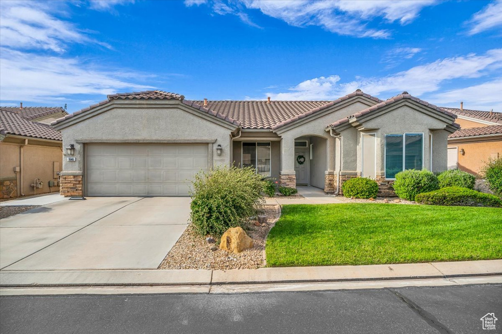 View of front of property featuring stucco siding, an attached garage, driveway, and stone siding