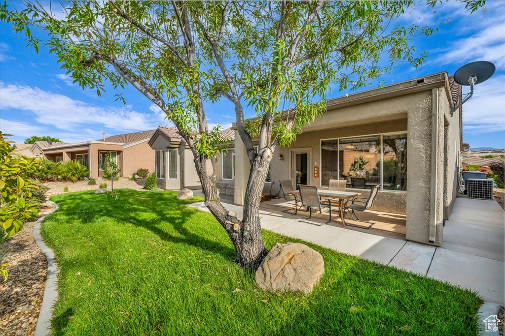 Rear view of house with stucco siding, a patio area, and a lawn