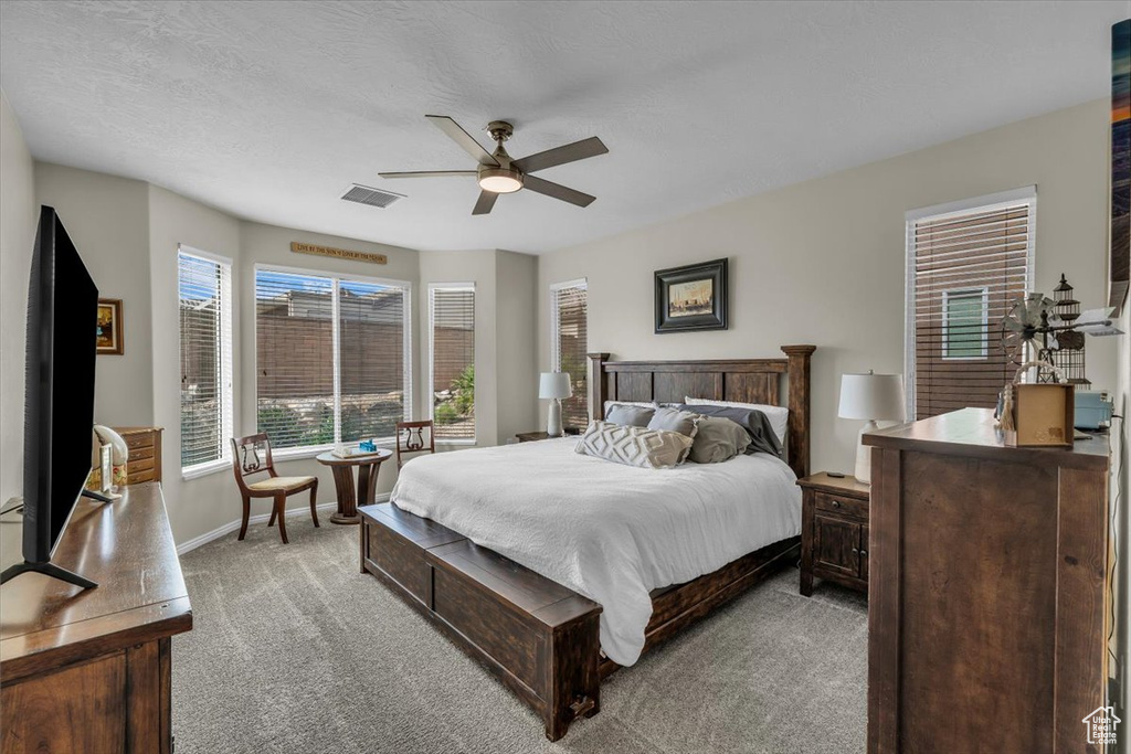 Bedroom with light colored carpet, baseboards, and ceiling fan