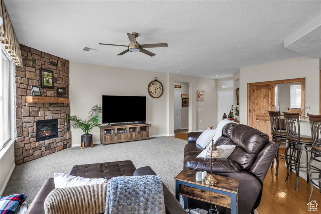 Living room featuring a ceiling fan, a fireplace, and baseboards