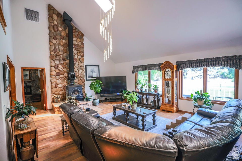 Living area with a wood stove, wood finished floors, and high vaulted ceiling