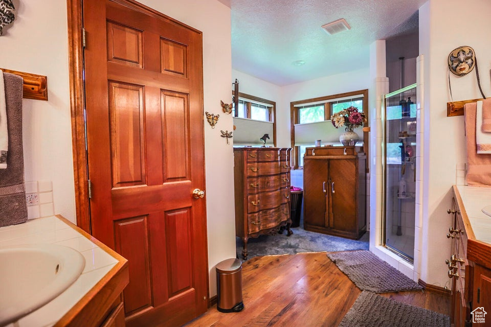 Bathroom featuring two vanities, wood finished floors, and a shower stall