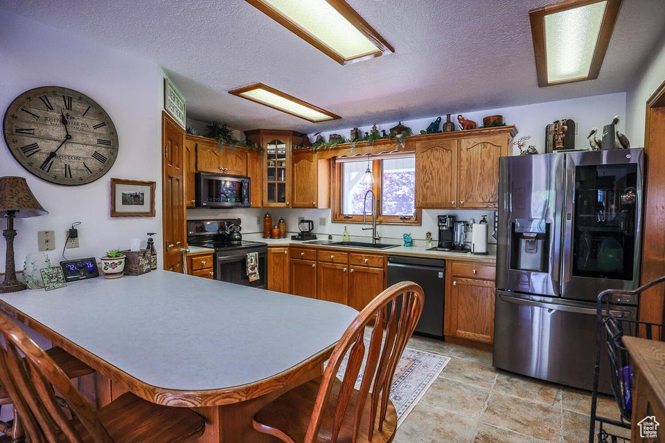 Kitchen featuring stainless steel fridge, dishwasher, black microwave, electric range oven, and a sink