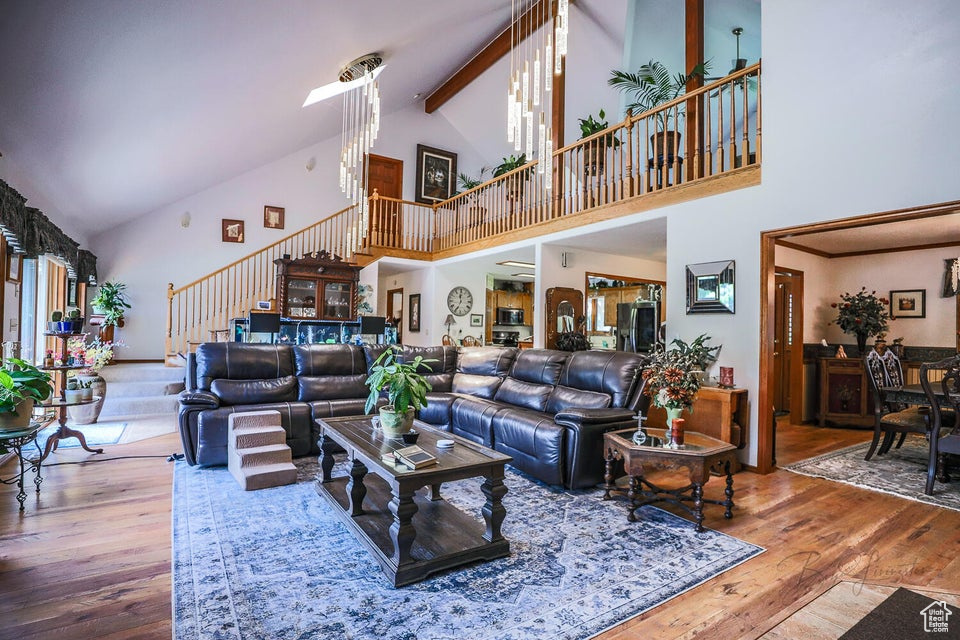Living room with high vaulted ceiling, stairway, hardwood / wood-style flooring, and beam ceiling