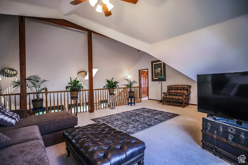 Living room featuring ceiling fan, lofted ceiling, and carpet flooring