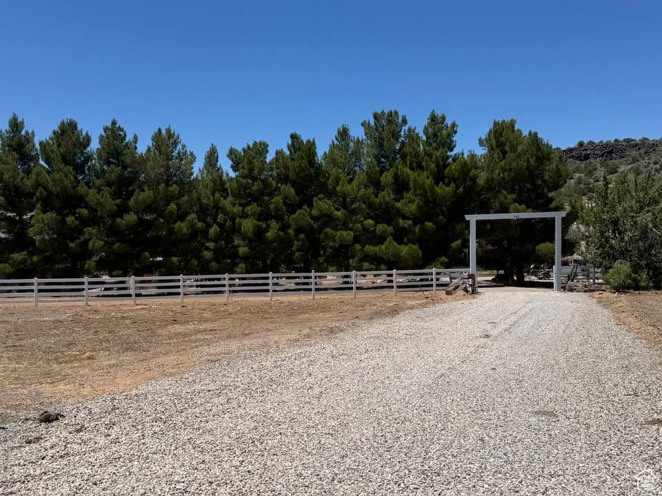 View of dirt / gravel driveway with an enclosed horse arena