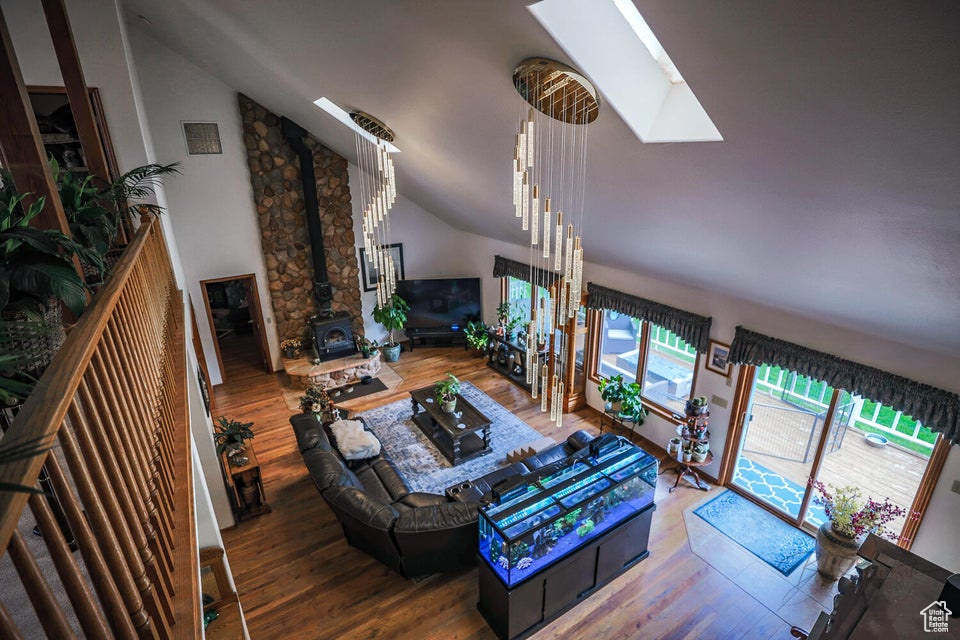 Living area featuring a wood stove, a skylight, wood finished floors, and lofted ceiling