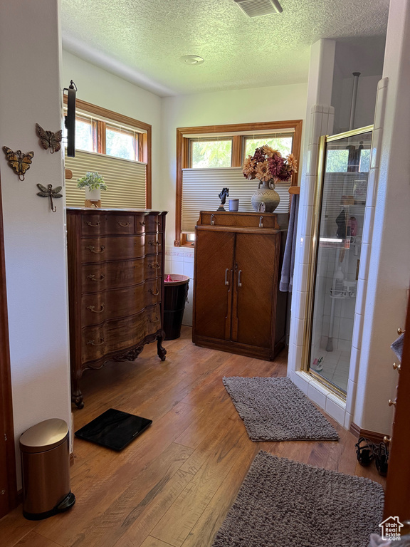 Bathroom featuring wood finished floors, a textured ceiling, a shower stall, and vanity