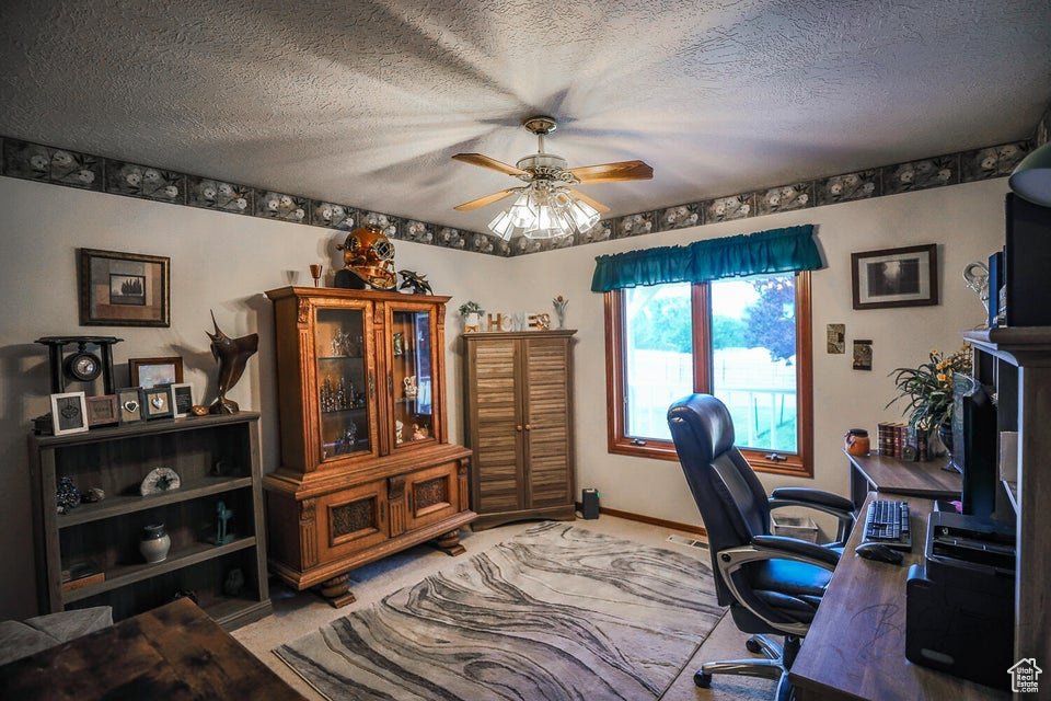 Office featuring ceiling fan, light carpet, a textured ceiling, and baseboards