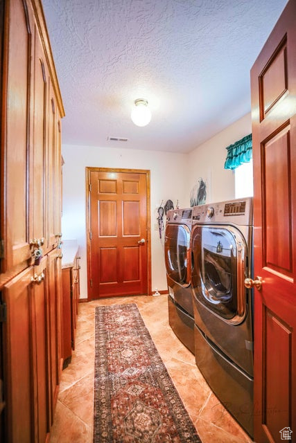 Washroom featuring washer and dryer and a textured ceiling