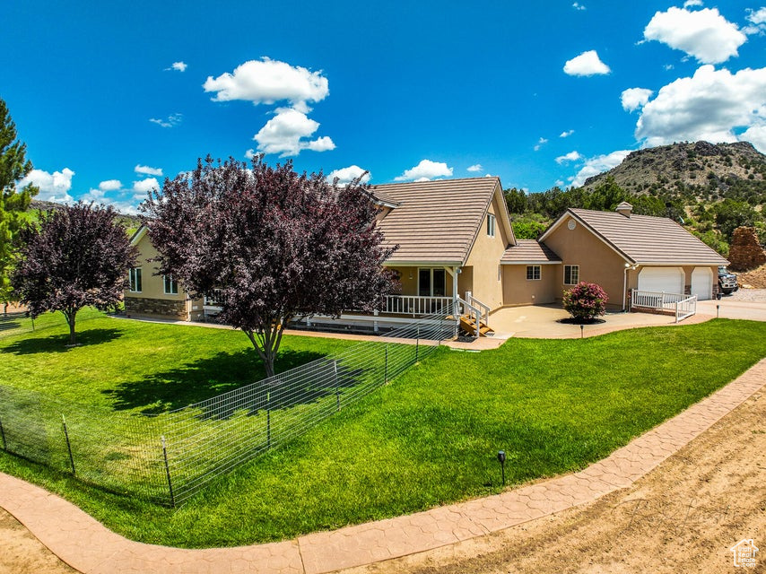 Back of property with stucco siding, a tiled roof, driveway, a mountain view, and a garage