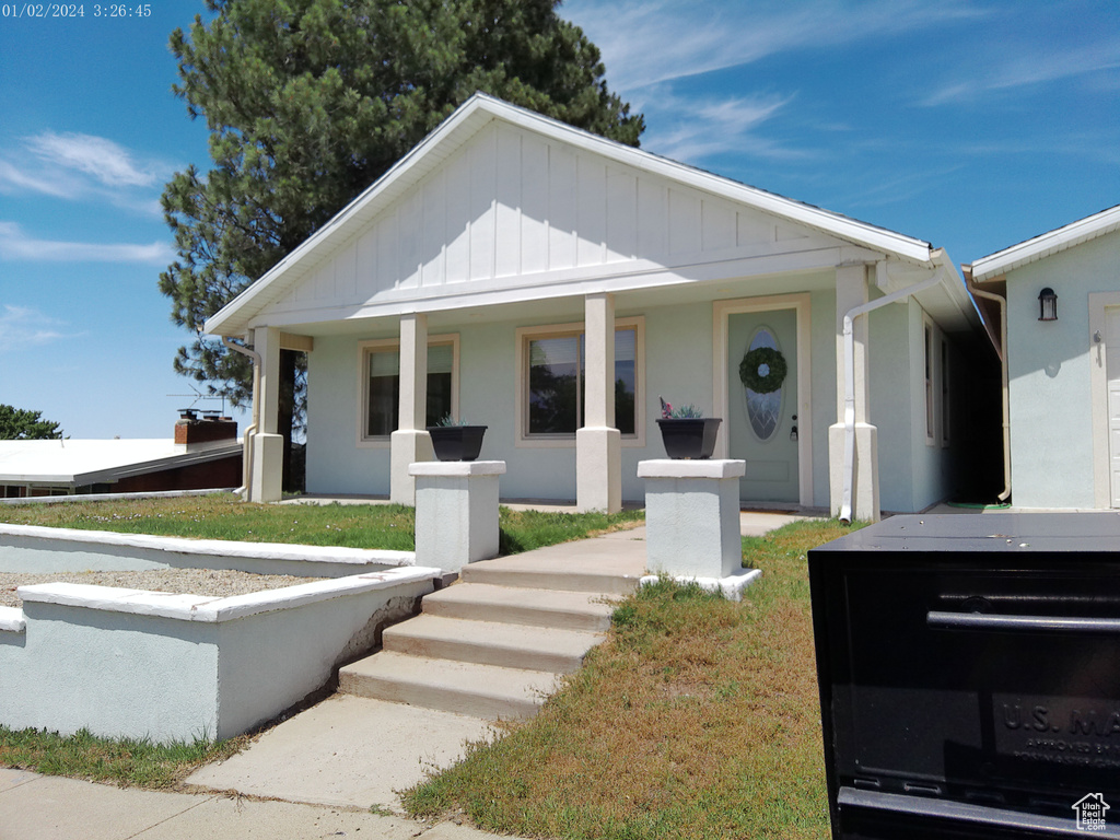 Bungalow featuring a porch and stucco siding